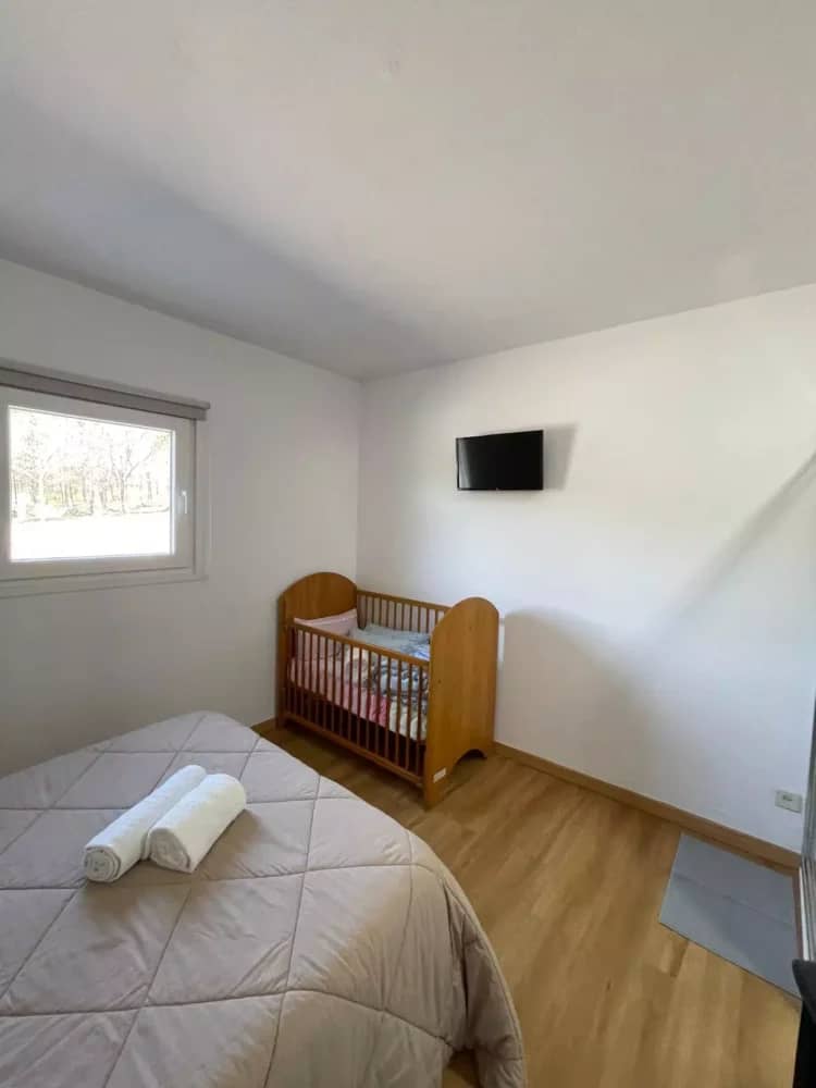 Quarto da Quinta Cerqueira com cama de casal, berço de madeira e televisão