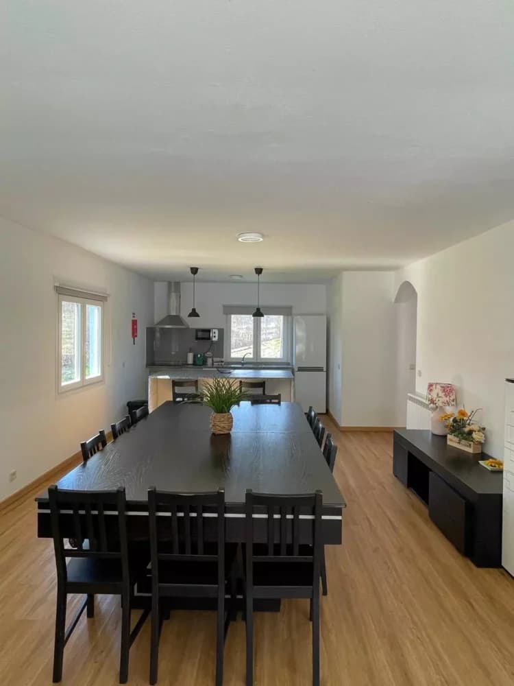 Sala de jantar da Quinta Cerqueira, com mesa comprida para doze pessoas e a cozinha em open space ao fundo