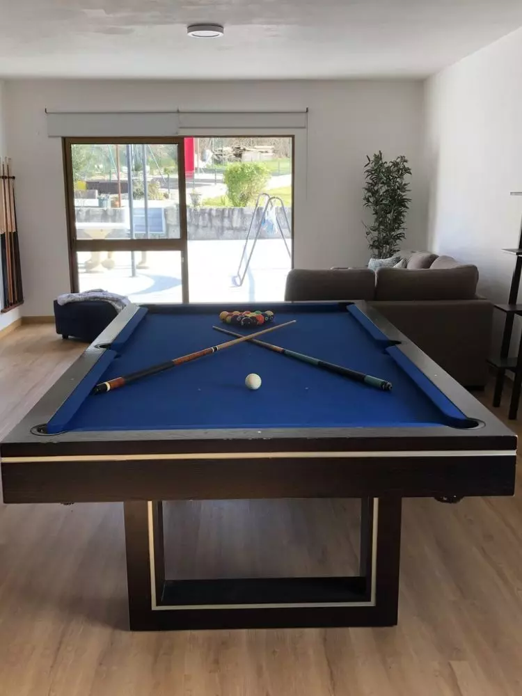 Sala de estar da Quinta Cerqueira com sofá, mesa de snooker e porta envidraçada para a piscina
